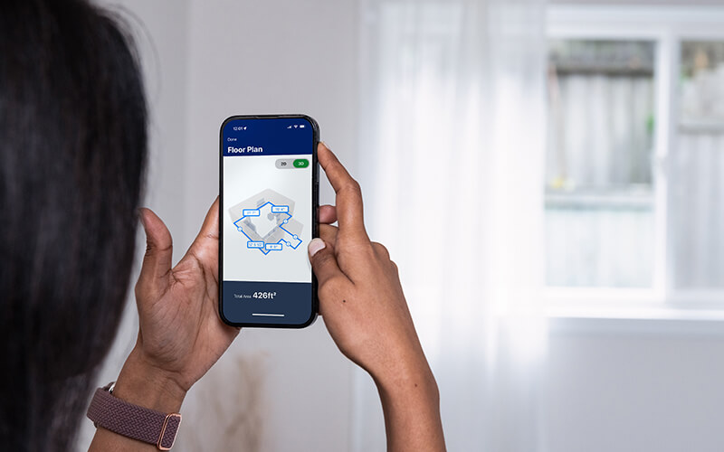 Woman using mobile phone and Lowes App to measure room